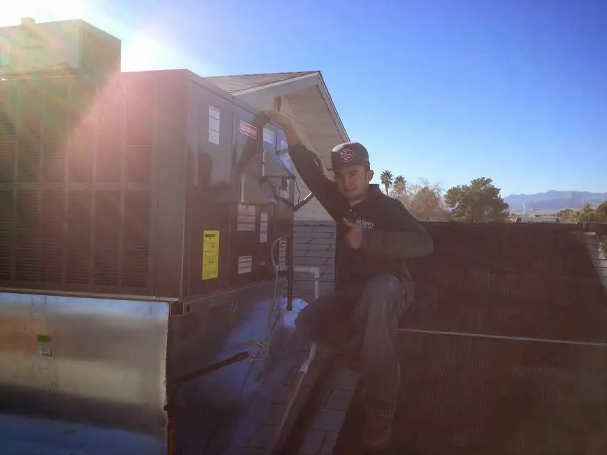 HVAC technician performing Air Duct Cleaning on a rooftop unit in Offutt AFB
